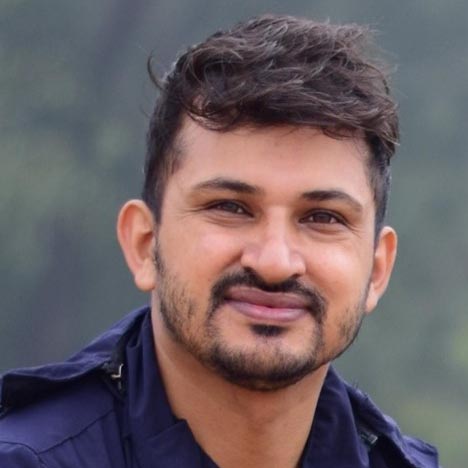 Head shot of a smiling Nepali man with beard and moustache