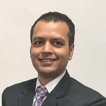 Head shot of a smiling Nepali man in a suit, shirt and tie